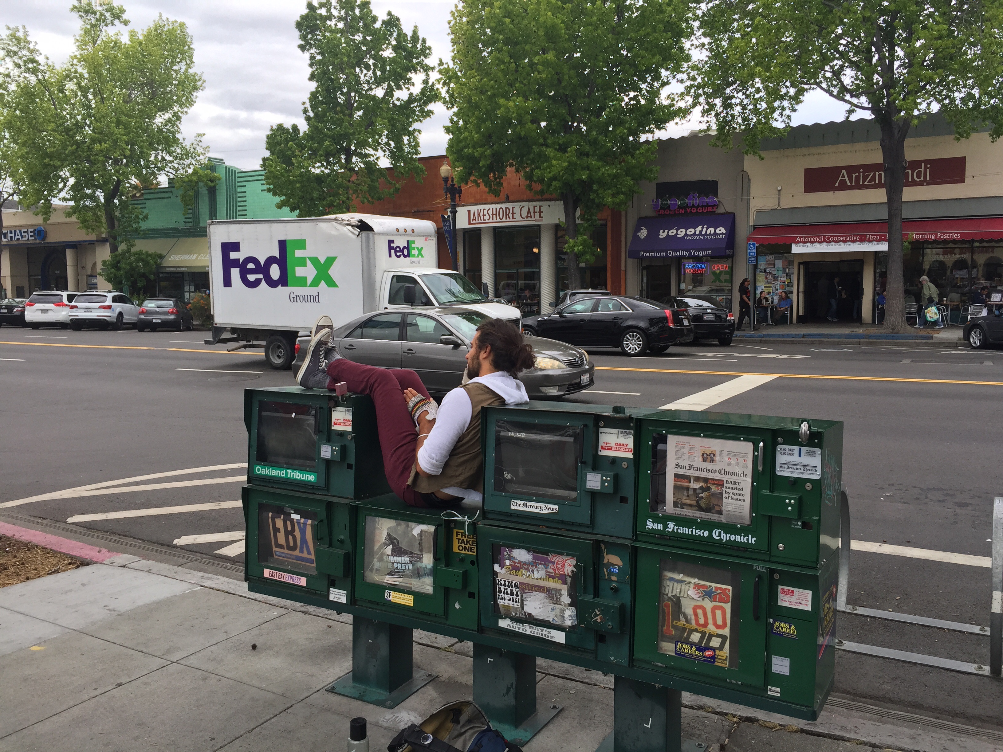 Man resting on top of newspaper vending machines